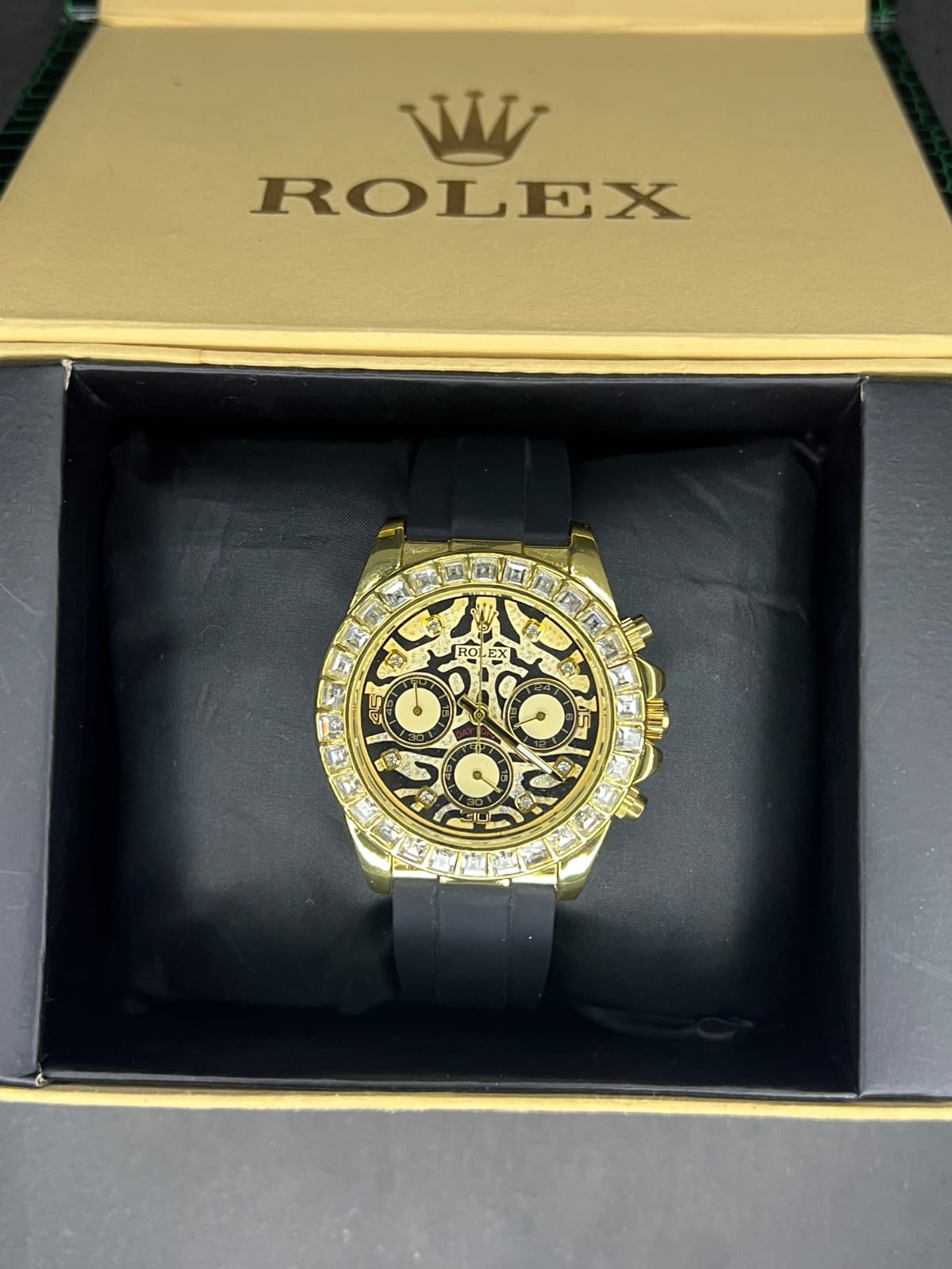 Rolex Oyster Perpetual Cosmograph Daytona with a black dial, gold casing, and a black strap.